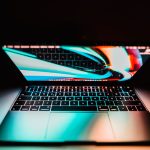 Photo of a laptop with a colorful screen and keys illuminated in soft light