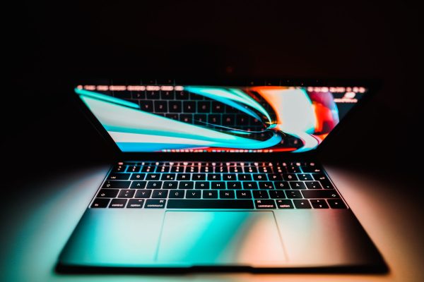 Photo of a laptop with a colorful screen and keys illuminated in soft light